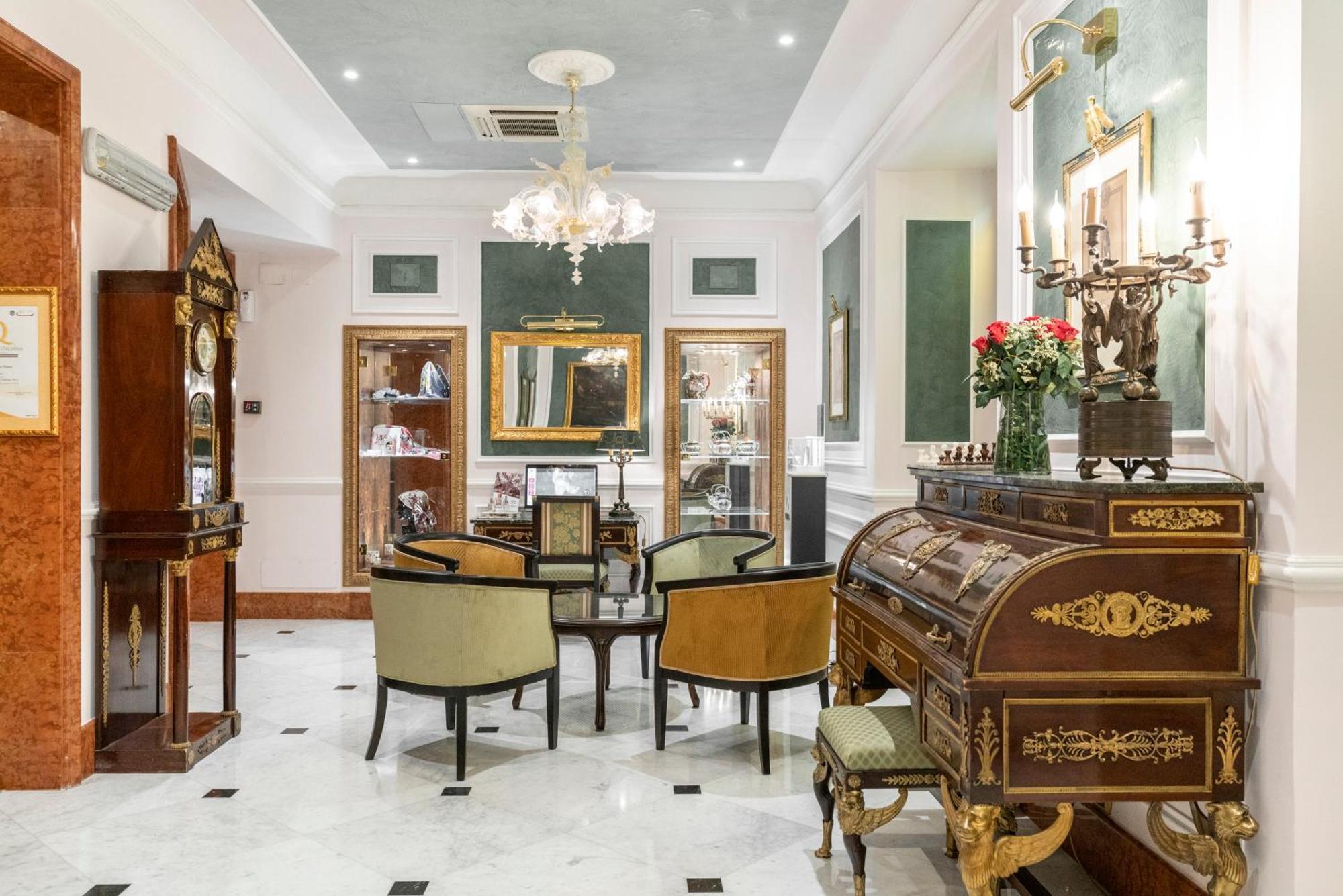Hotel Bristol Palace Genova Esterno foto The photo shows an elegantly furnished room that appears to function as a sitting area or parlor. The space features a chandelier hanging from the ceiling, providing soft lighting. In the center, there is a round table surrounded by upholstered chair