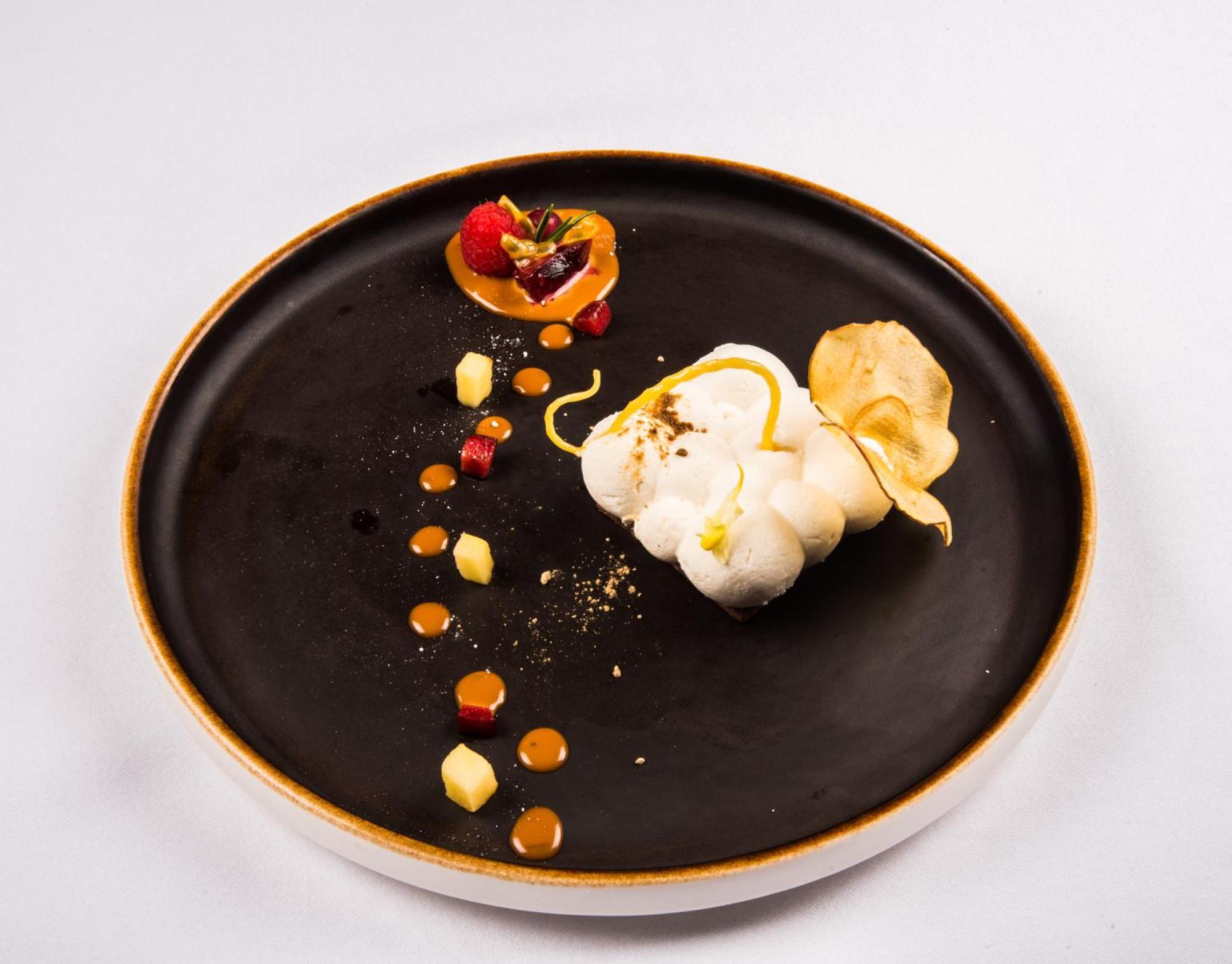 Hotel Bristol Palace Genova Esterno foto The photo features a beautifully arranged plate of gourmet food. On a dark plate, there is a white, fluffy dessert, possibly a meringue or a mousse, that is artistically shaped. Surrounding it are various colorful components, including small dots of 