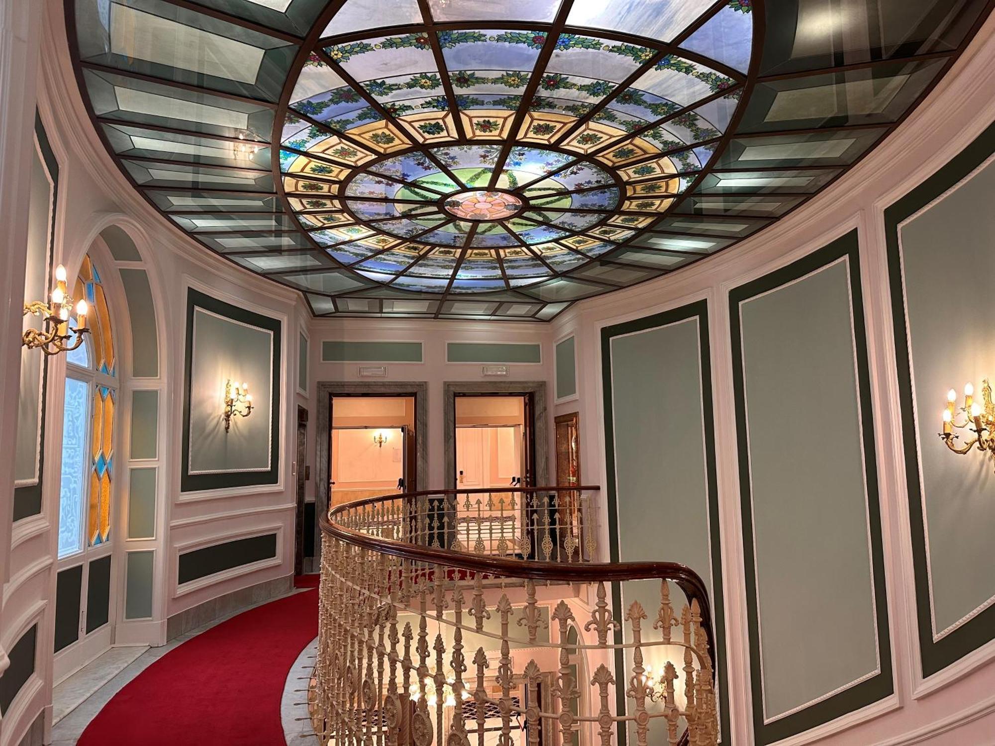 Hotel Bristol Palace Genova Esterno foto The photograph shows an elegantly designed interior space with a round balcony area. The ceiling is adorned with a large, intricate stained glass design that features various colors and patterns, creating a visually striking focal point. The walls ar