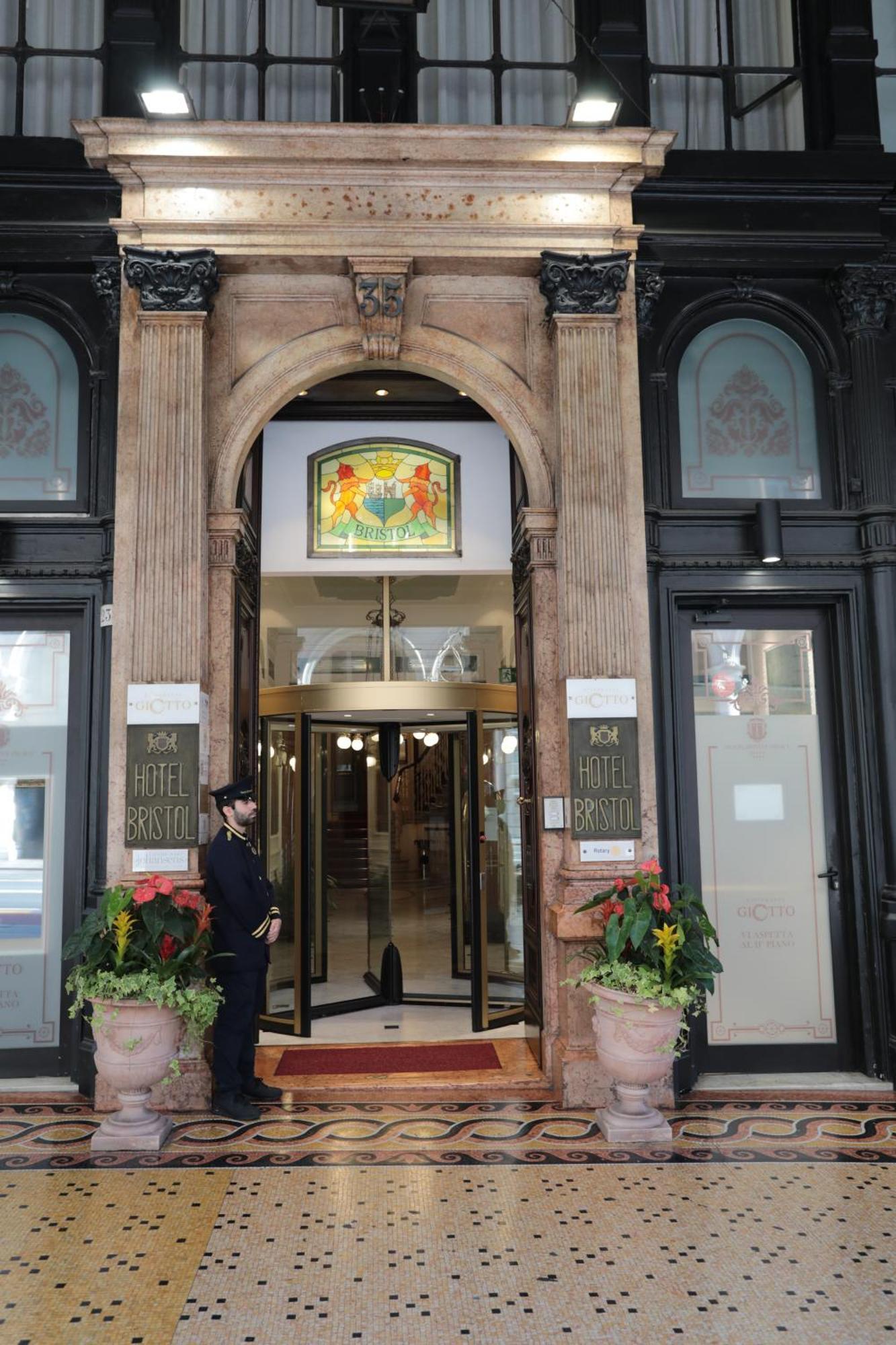 Hotel Bristol Palace Genova Esterno foto The photo shows the entrance of a hotel, specifically the "Hotel Bristol." The entrance features an ornate archway with decorative elements. Above the main door, there is a stained glass window with colorful designs. To the sides of the entrance, the